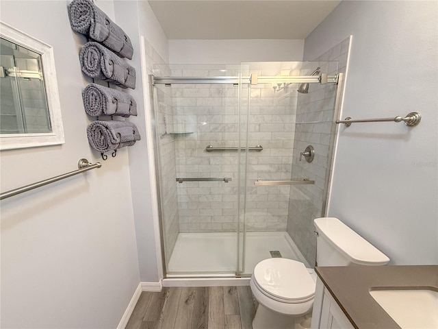 bathroom with vanity, wood-type flooring, a shower with door, and toilet