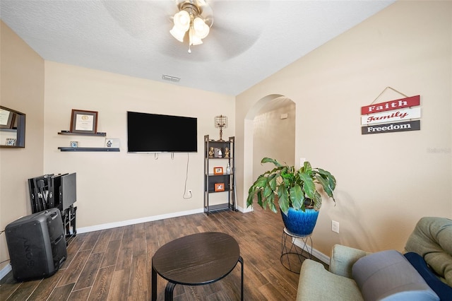 living room with ceiling fan, a textured ceiling, and dark hardwood / wood-style flooring