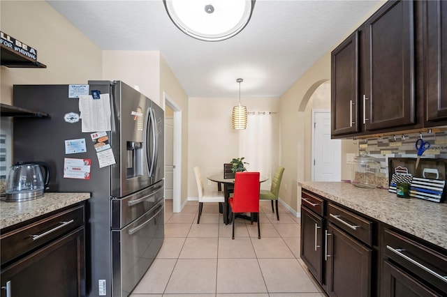 kitchen with stainless steel fridge with ice dispenser, light tile patterned floors, dark brown cabinetry, and decorative light fixtures