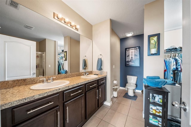 bathroom featuring vanity, toilet, a shower with shower door, and tile patterned flooring