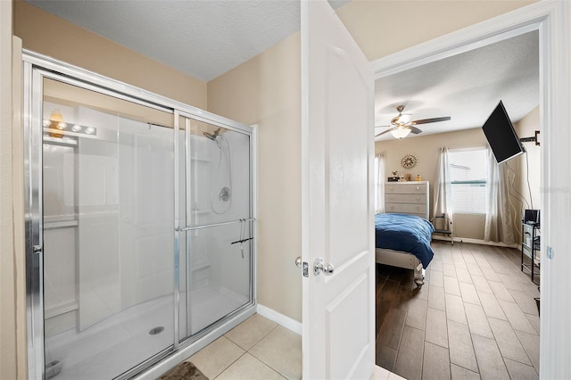 bathroom with ceiling fan, wood-type flooring, a shower with shower door, and a textured ceiling