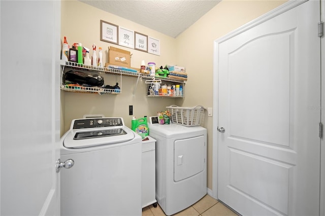 laundry room with washer and clothes dryer, a textured ceiling, and light tile patterned floors