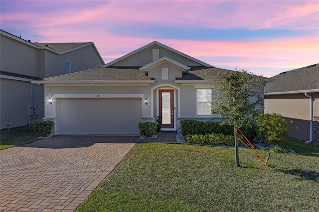 ranch-style home with a garage and a lawn