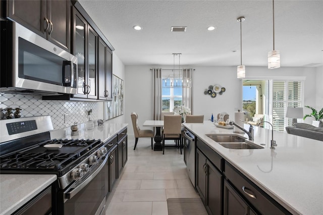 kitchen with tasteful backsplash, appliances with stainless steel finishes, sink, and hanging light fixtures