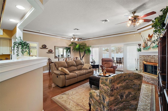 living room with ornamental molding, a textured ceiling, ceiling fan, and a fireplace