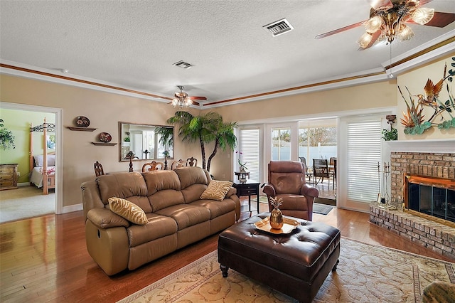 living room featuring ceiling fan, a fireplace, light hardwood / wood-style floors, and a textured ceiling