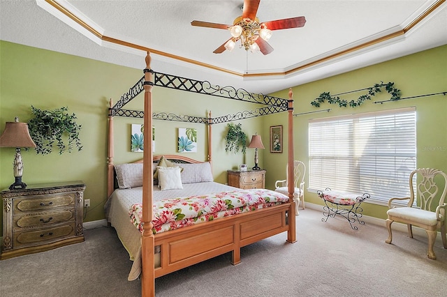 bedroom with crown molding, carpet flooring, a tray ceiling, and a textured ceiling