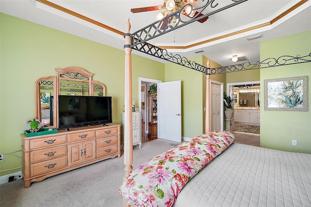 carpeted bedroom with ceiling fan, ensuite bath, and a tray ceiling