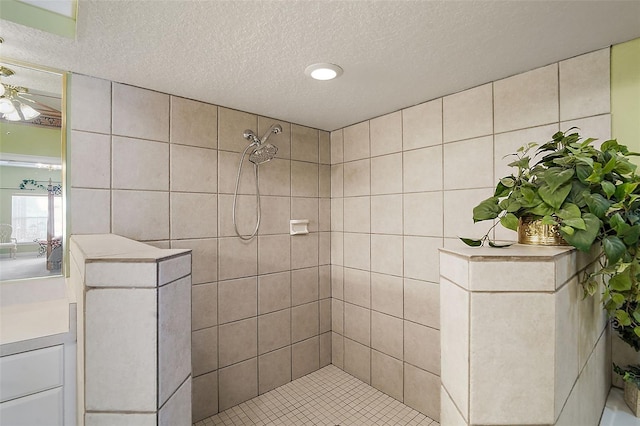 bathroom featuring vanity, ceiling fan, a textured ceiling, and a tile shower