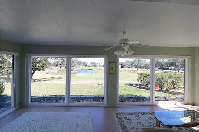 unfurnished sunroom with a water view, ceiling fan, and a wealth of natural light