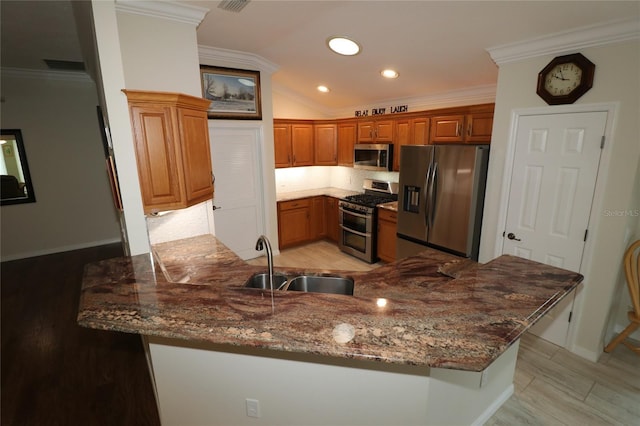 kitchen featuring stainless steel appliances, kitchen peninsula, sink, and dark stone counters