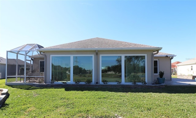 back of property featuring glass enclosure and a lawn