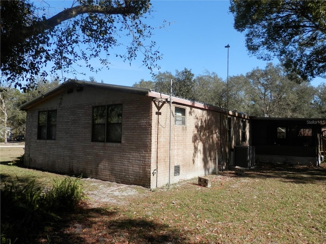 view of side of property with central air condition unit and a lawn