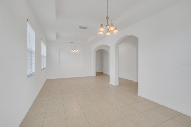 unfurnished room featuring a tray ceiling, a chandelier, and light tile patterned flooring