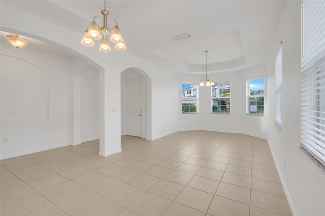 unfurnished dining area featuring a raised ceiling, light tile patterned floors, and a chandelier