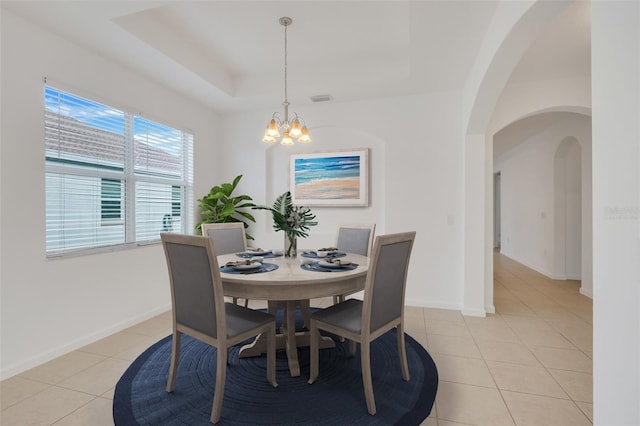 dining space featuring a raised ceiling, light tile patterned floors, and a chandelier