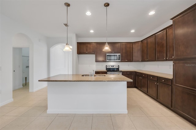 kitchen featuring pendant lighting, sink, a kitchen island with sink, stainless steel appliances, and light stone counters