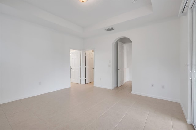 empty room featuring a tray ceiling and light tile patterned floors