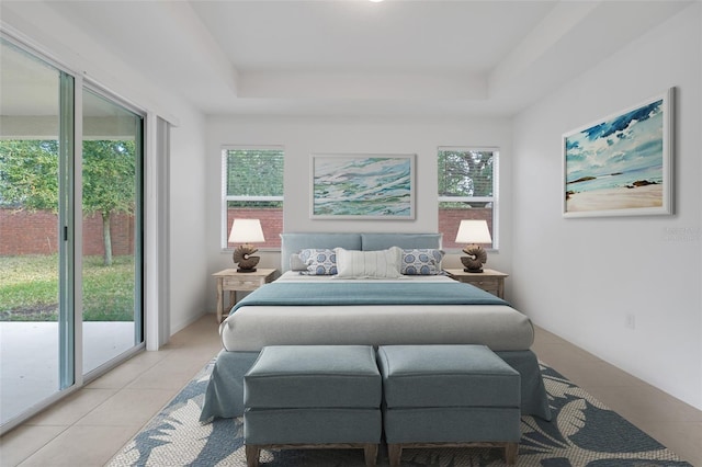 bedroom with light tile patterned floors, access to exterior, and a tray ceiling