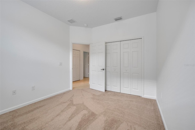 unfurnished bedroom with light carpet and a closet