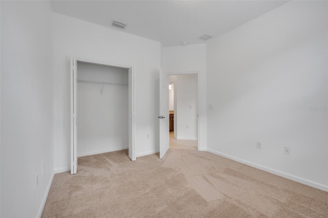 unfurnished bedroom featuring light colored carpet and a closet