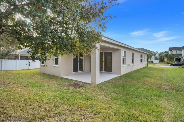 rear view of house featuring a lawn and a patio