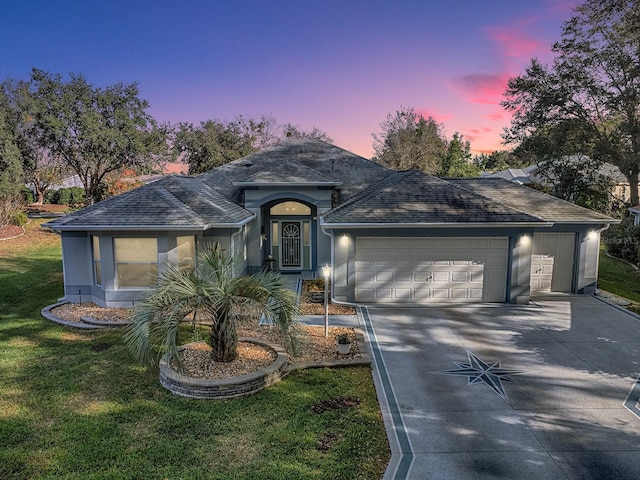 ranch-style home with a garage and a lawn