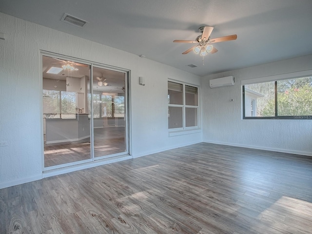 empty room with ceiling fan, hardwood / wood-style flooring, and a wall mounted AC