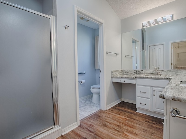 bathroom featuring a shower with door, vanity, wood-type flooring, a textured ceiling, and toilet