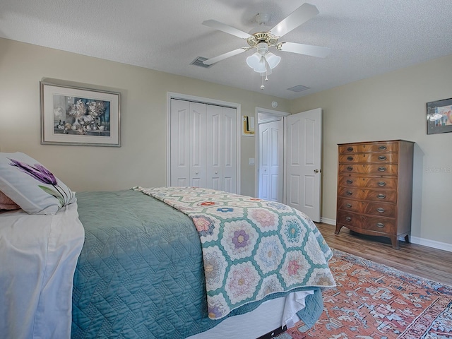 bedroom featuring ceiling fan, wood-type flooring, a closet, and a textured ceiling