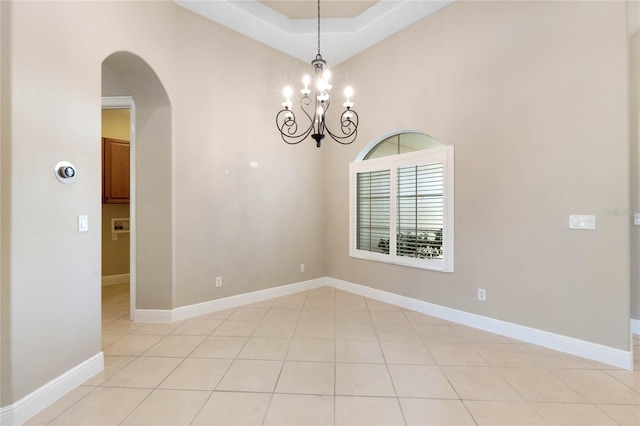 unfurnished room with light tile patterned floors, an inviting chandelier, and a tray ceiling