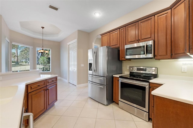 kitchen with pendant lighting, light tile patterned floors, stainless steel appliances, a tray ceiling, and a chandelier