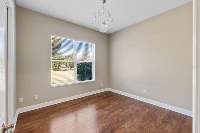 spare room featuring a notable chandelier and dark hardwood / wood-style flooring