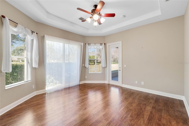 spare room with dark wood-type flooring, ceiling fan, and a tray ceiling