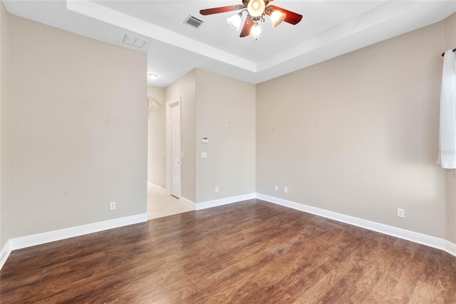 spare room featuring light hardwood / wood-style flooring, ceiling fan, and a tray ceiling