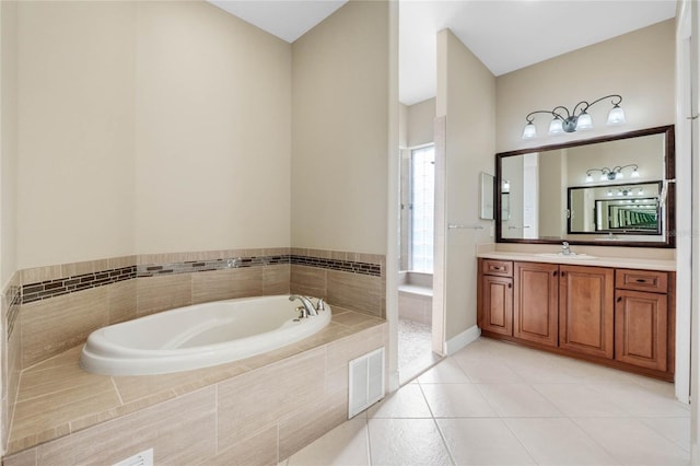 bathroom with tile patterned flooring, tiled tub, and vanity