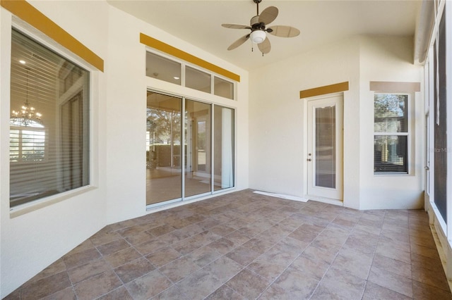 unfurnished sunroom with plenty of natural light and ceiling fan with notable chandelier