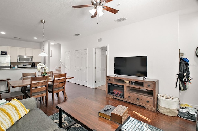 living room featuring dark wood-type flooring and ceiling fan