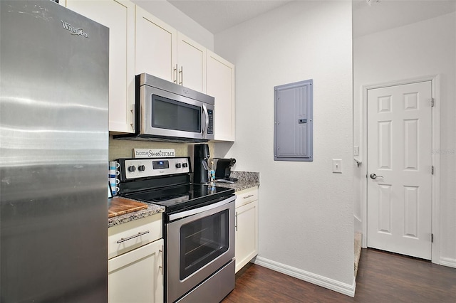 kitchen with dark wood-type flooring, appliances with stainless steel finishes, white cabinetry, electric panel, and light stone countertops