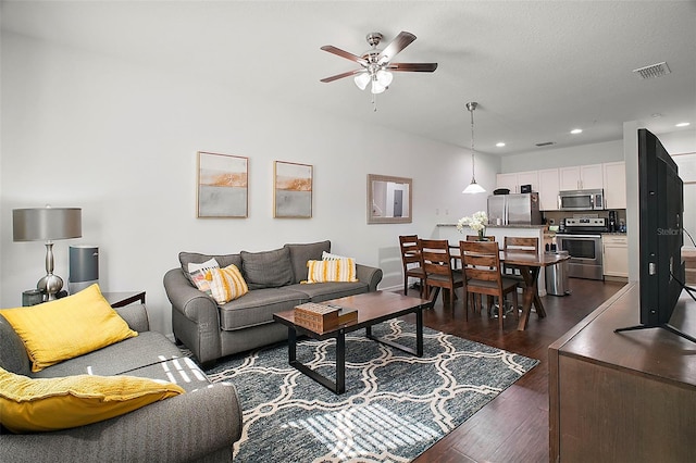 living room with ceiling fan and dark hardwood / wood-style flooring