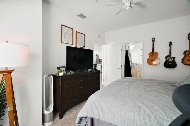 bedroom featuring ceiling fan, light colored carpet, and ensuite bath