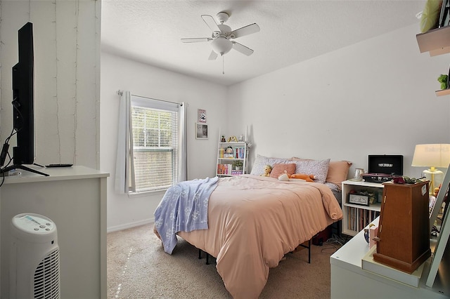 carpeted bedroom featuring ceiling fan and a textured ceiling