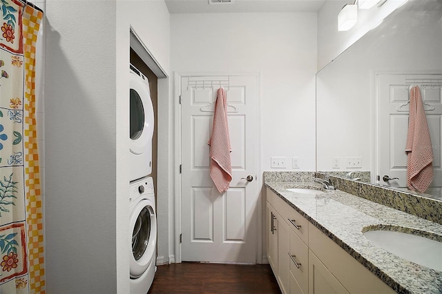 washroom featuring stacked washer and clothes dryer, sink, and dark hardwood / wood-style floors