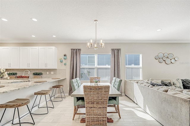 dining room with sink, crown molding, a notable chandelier, a textured ceiling, and light wood-type flooring