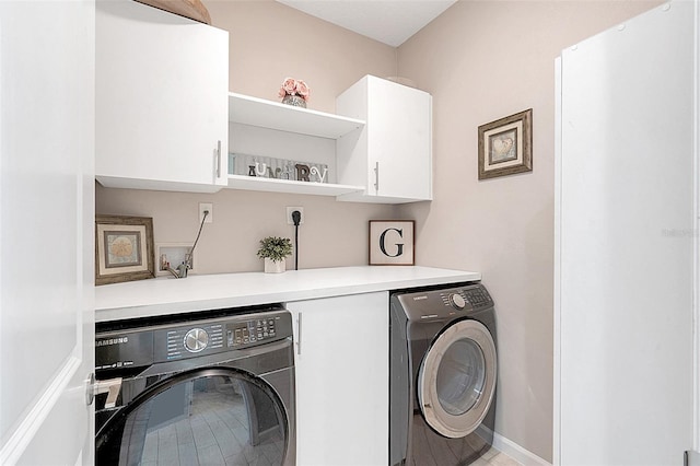 clothes washing area featuring independent washer and dryer and cabinets