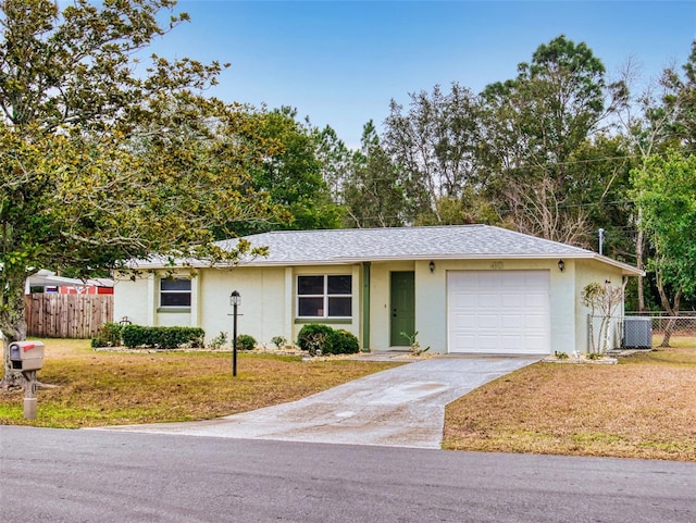 ranch-style home with a garage, a front yard, and central air condition unit