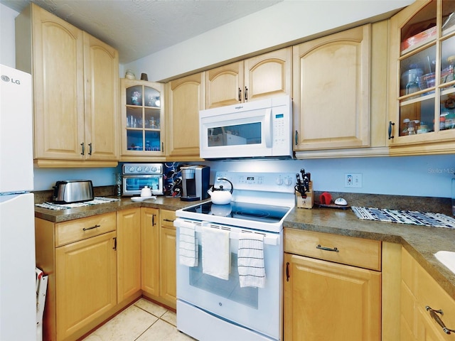 kitchen featuring light brown cabinetry, light tile patterned floors, and white appliances