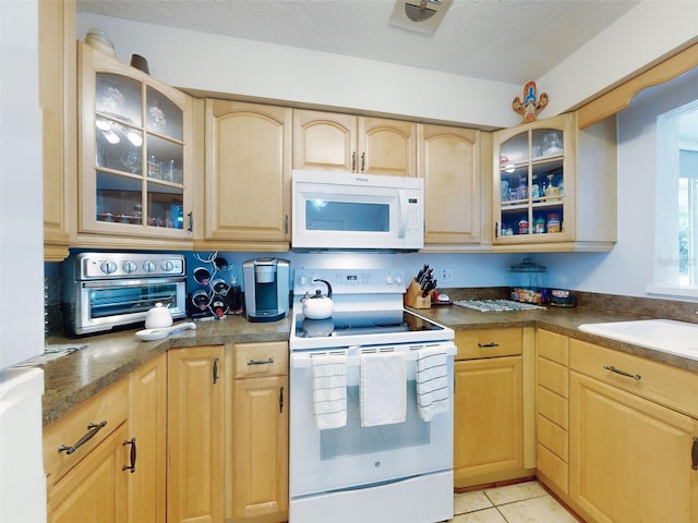 kitchen with sink, white appliances, a textured ceiling, light tile patterned flooring, and light brown cabinets