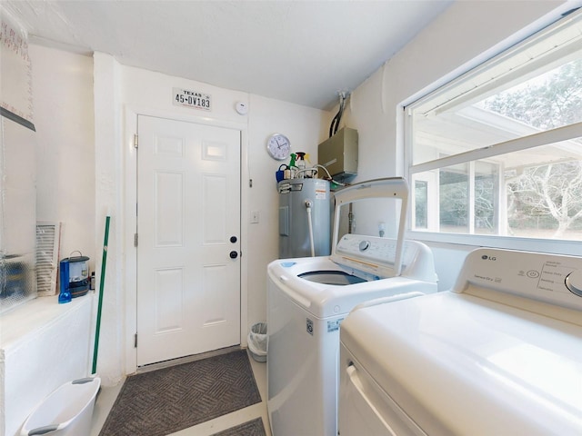 washroom featuring separate washer and dryer, electric water heater, and a wealth of natural light