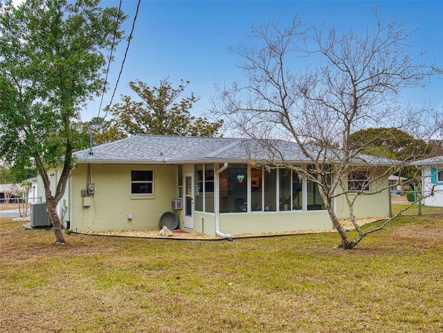 rear view of property featuring cooling unit, a lawn, and a sunroom